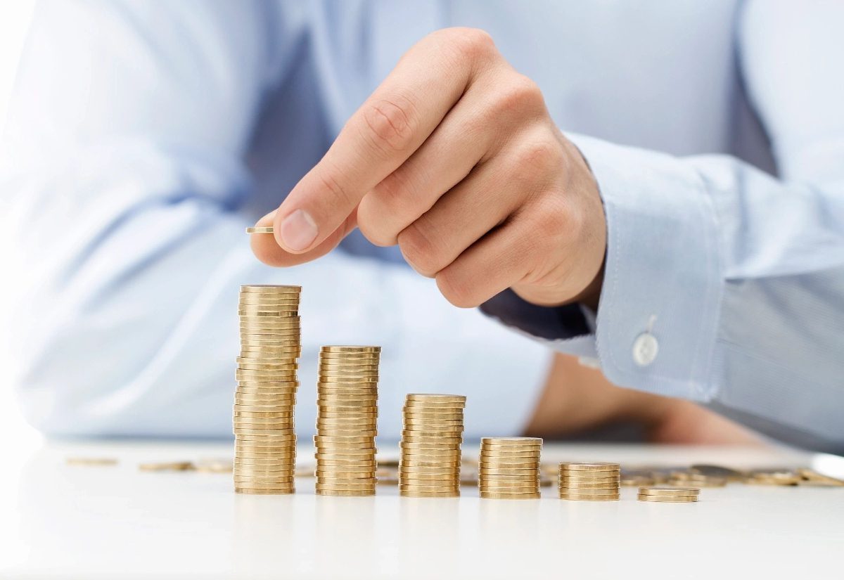 A person is putting money in stacks of coins.